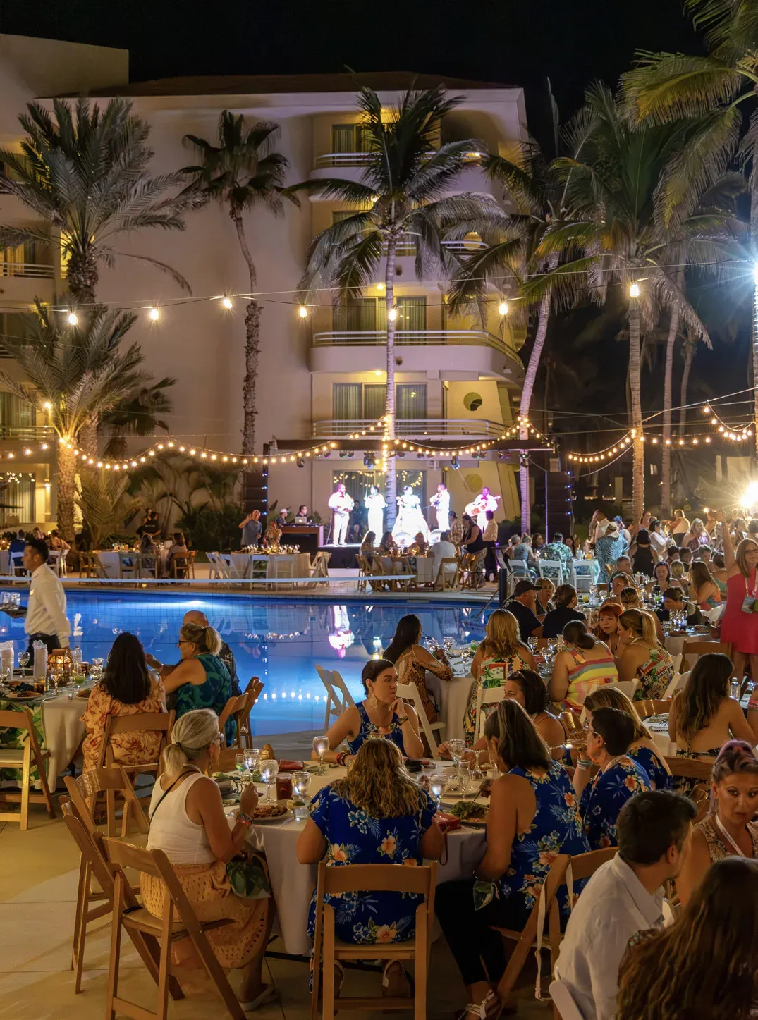 Evening dinner on the resort terrace, with a stage and the hotel lit up behind the pool