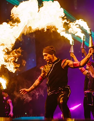 performers on a dark stage twirling fire